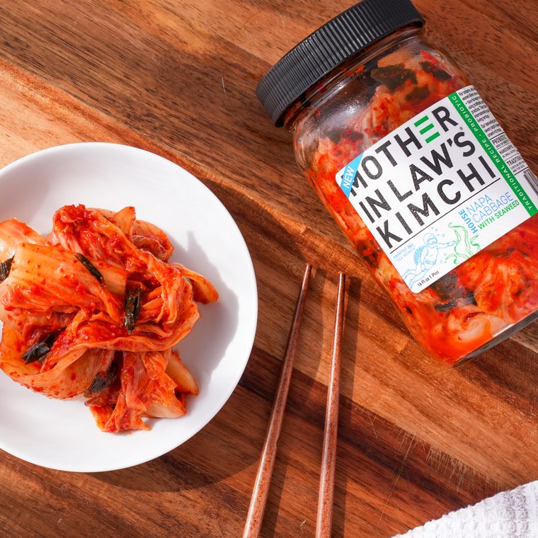 Seaweed kimchi served on a white plate beside the jar and chopsticks on a wooden board
